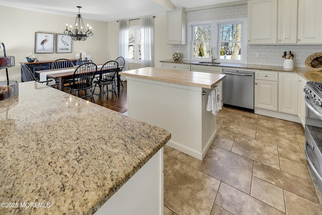 kitchen featuring stainless steel appliances, sink, a kitchen island, and white cabinets