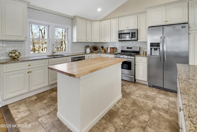 kitchen with a kitchen island, wood counters, sink, white cabinets, and stainless steel appliances