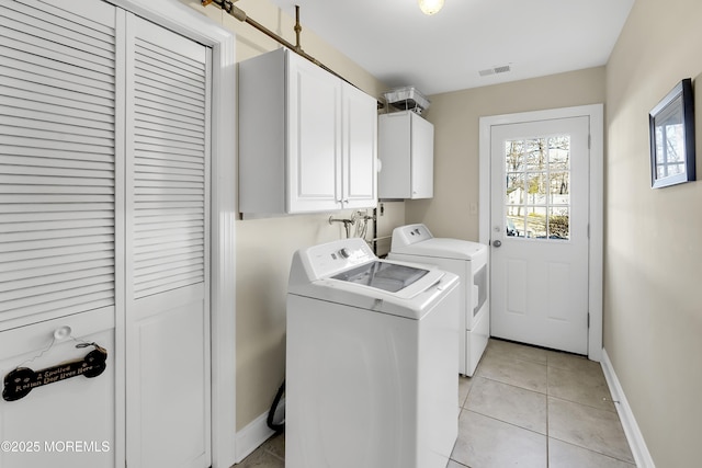 laundry area featuring cabinets, light tile patterned flooring, and washer and dryer