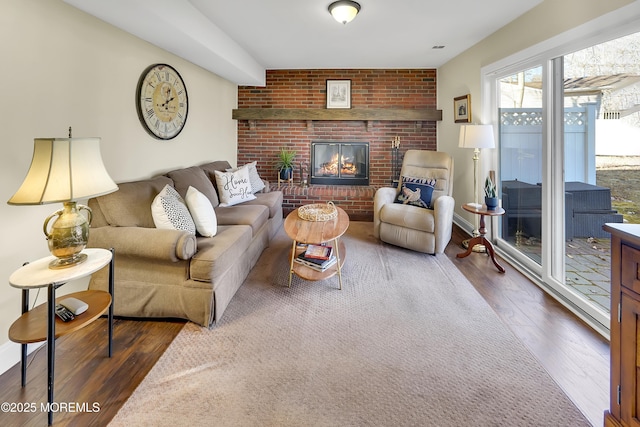 living room featuring a brick fireplace and dark wood-type flooring