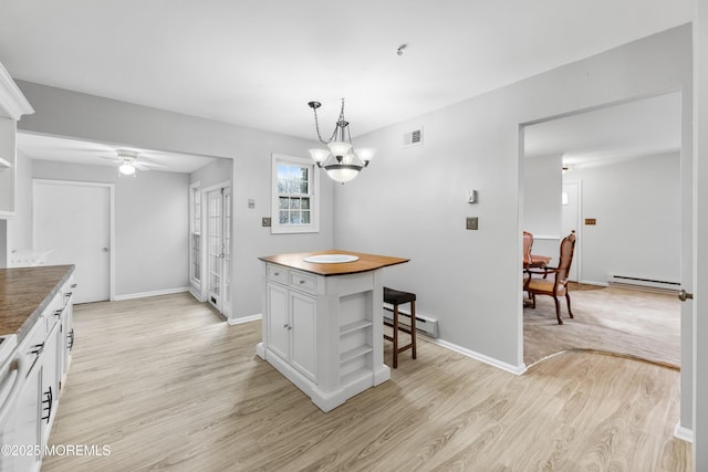 kitchen with white cabinetry, pendant lighting, baseboard heating, and light hardwood / wood-style floors