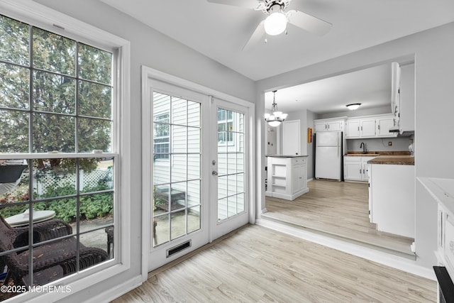 entryway featuring french doors, ceiling fan with notable chandelier, light hardwood / wood-style floors, and sink