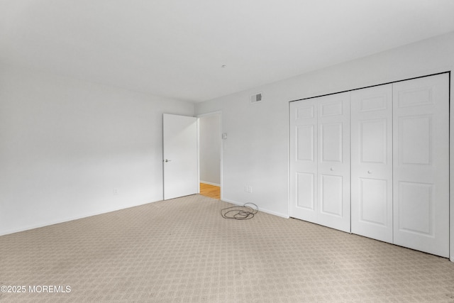 unfurnished bedroom with light colored carpet and a closet