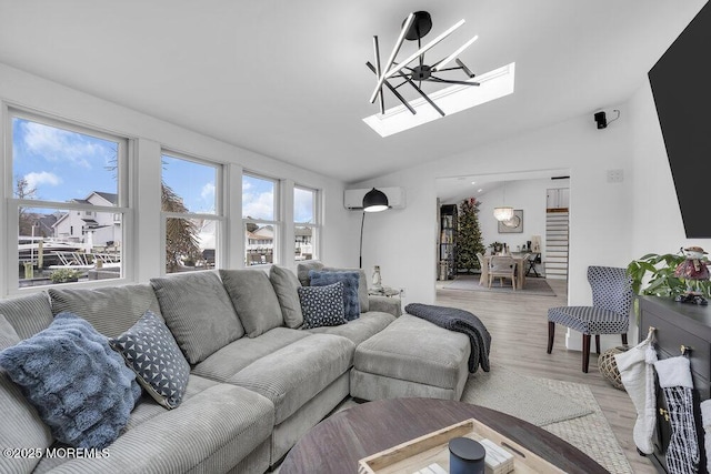 living room featuring lofted ceiling with skylight, light wood-type flooring, ceiling fan, and a wall unit AC