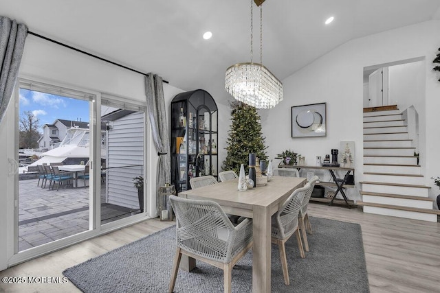 dining room with vaulted ceiling, light hardwood / wood-style flooring, and a notable chandelier