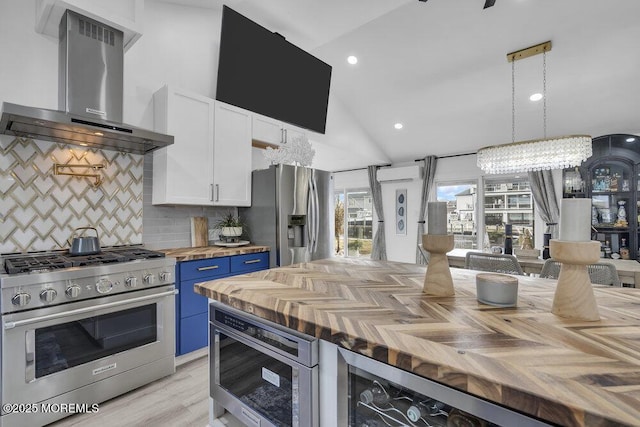 kitchen with wood counters, wall chimney exhaust hood, blue cabinets, stainless steel appliances, and white cabinets