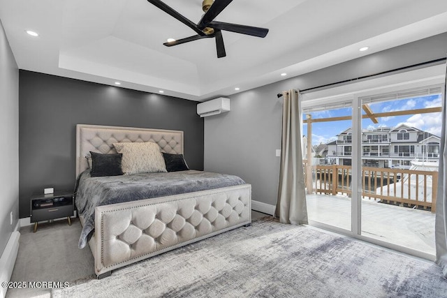 bedroom with ceiling fan, access to exterior, a tray ceiling, carpet floors, and an AC wall unit