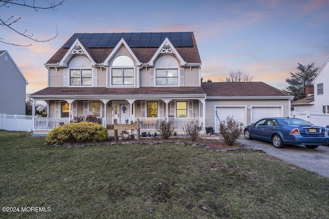 view of front of home featuring a yard, a garage, solar panels, and a porch