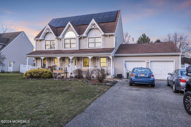 view of front of property with a garage, a lawn, covered porch, and solar panels