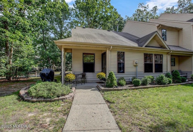 view of front facade featuring roof with shingles and a front yard