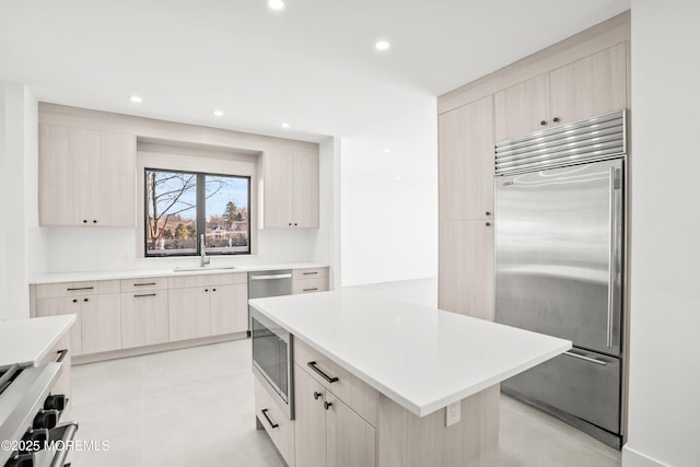 kitchen with a kitchen island, sink, built in appliances, and light brown cabinets