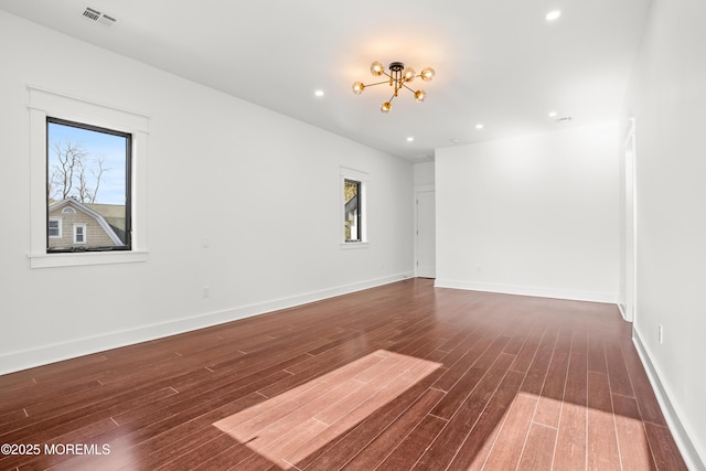 empty room with a notable chandelier and dark hardwood / wood-style floors