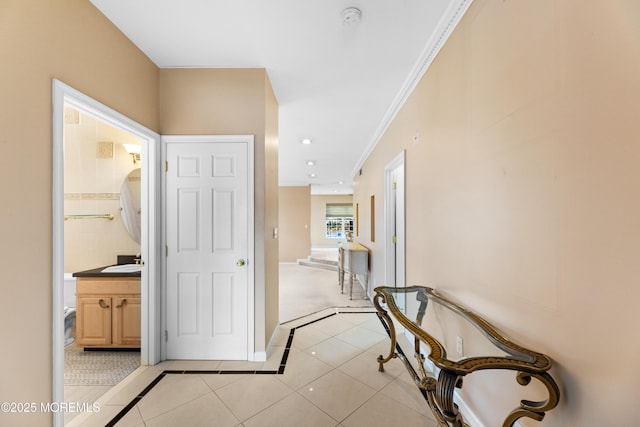 hall featuring sink, ornamental molding, and light tile patterned flooring