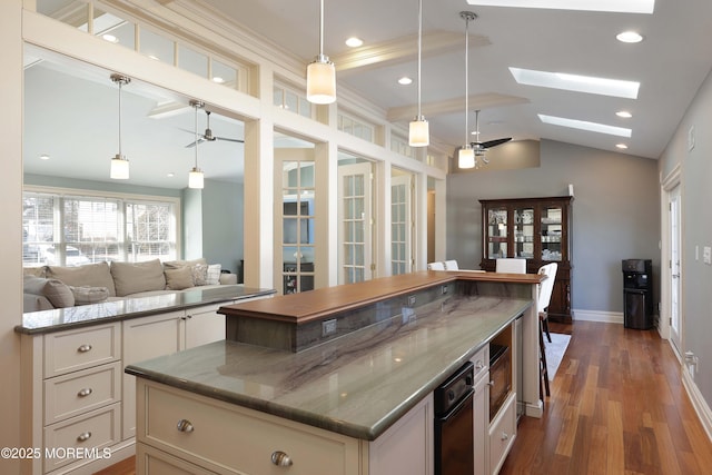 kitchen with dark stone countertops, decorative light fixtures, dark wood-type flooring, and ceiling fan