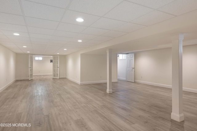 basement featuring a paneled ceiling and light wood-type flooring