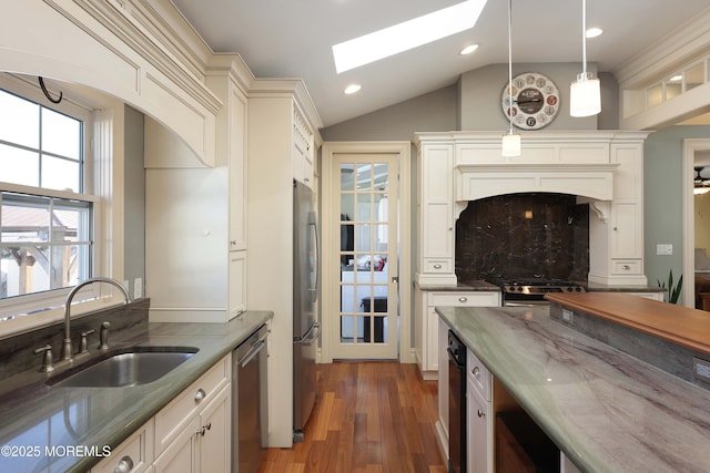 kitchen featuring sink, dark wood-type flooring, dark stone countertops, stainless steel appliances, and decorative light fixtures