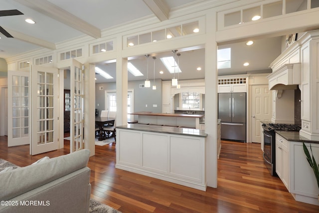 kitchen featuring beamed ceiling, appliances with stainless steel finishes, a skylight, and hanging light fixtures