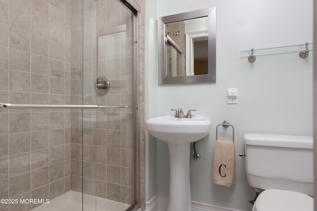 bathroom featuring a shower with door and toilet