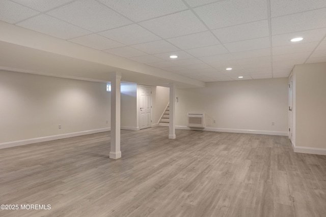 basement with a paneled ceiling and light hardwood / wood-style flooring