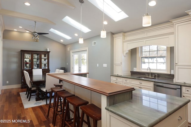 kitchen with sink, dishwasher, vaulted ceiling with skylight, french doors, and cream cabinetry