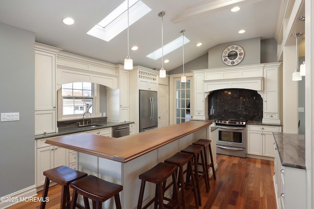 kitchen with sink, appliances with stainless steel finishes, dark hardwood / wood-style floors, vaulted ceiling with skylight, and backsplash