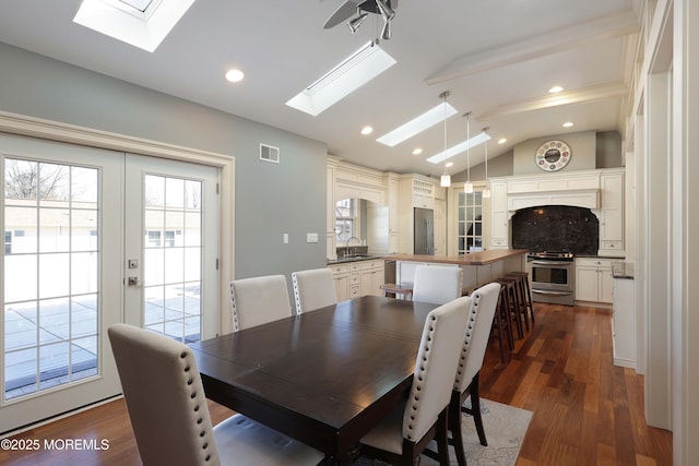 dining area with sink, dark wood-type flooring, lofted ceiling with skylight, and french doors