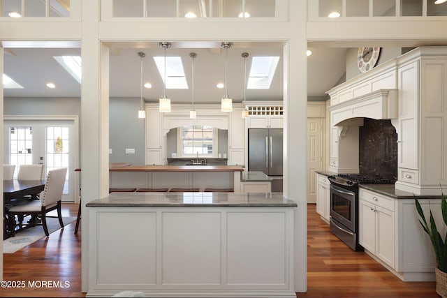 kitchen with appliances with stainless steel finishes, decorative light fixtures, dark hardwood / wood-style flooring, and sink