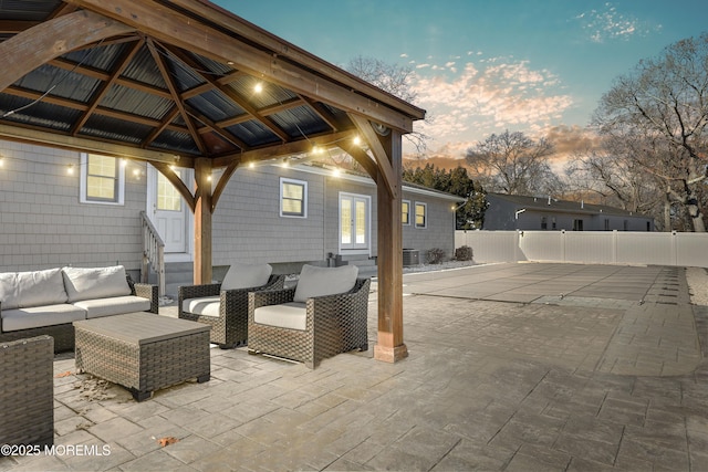 patio terrace at dusk featuring cooling unit, an outdoor living space, and a gazebo