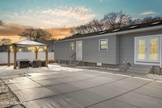 back house at dusk with french doors, a gazebo, an outdoor hangout area, and a patio area