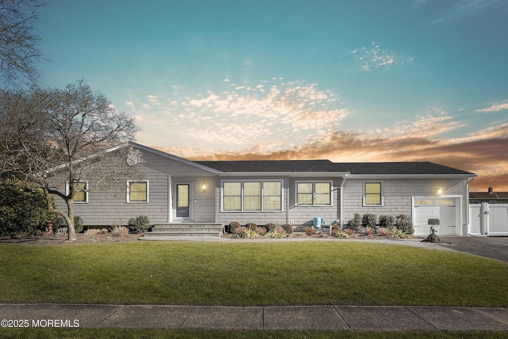 ranch-style home featuring a garage and a lawn