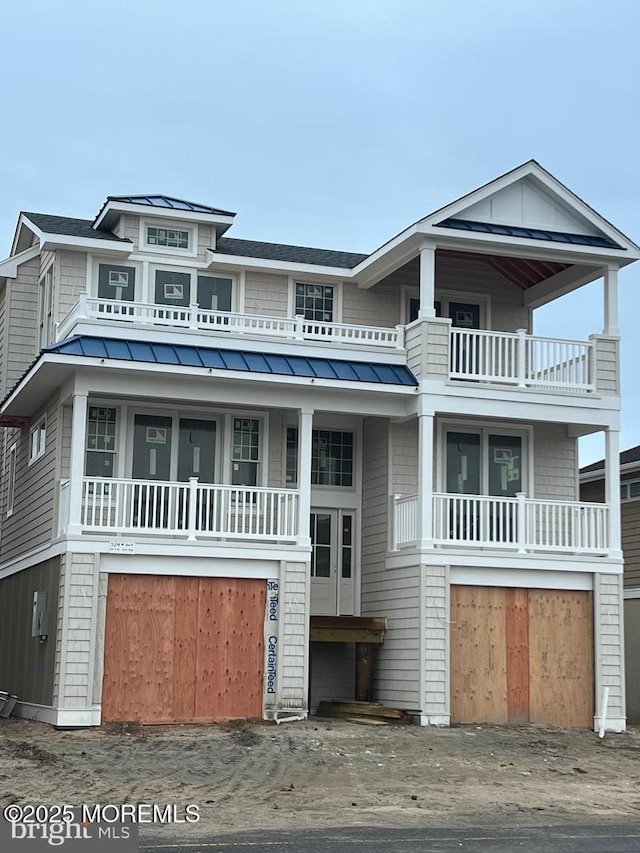 view of front of property featuring metal roof, a shingled roof, a standing seam roof, and a balcony