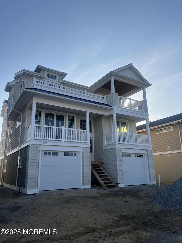 view of front of home with an attached garage, dirt driveway, and stairs