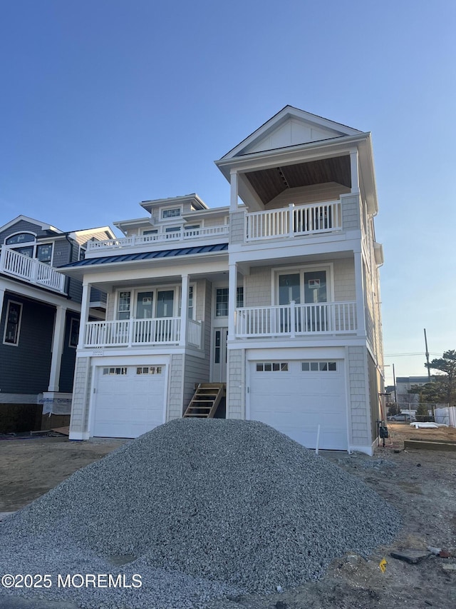 beach home with a standing seam roof, metal roof, a balcony, and an attached garage