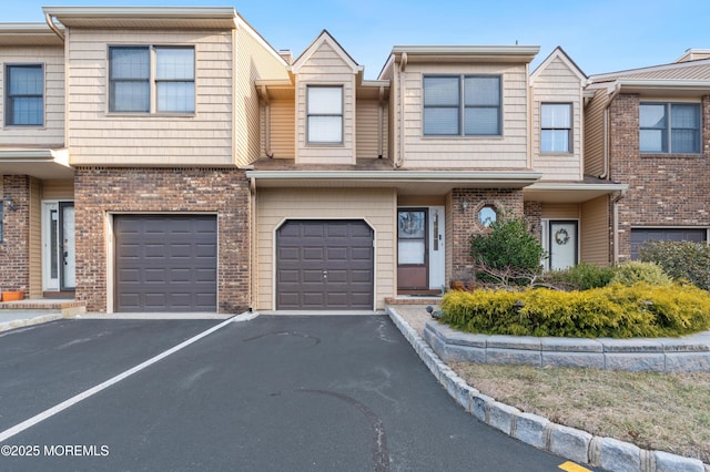 view of property featuring driveway, a garage, and brick siding