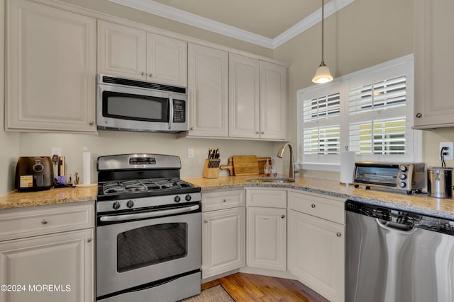 kitchen featuring sink, appliances with stainless steel finishes, light stone counters, ornamental molding, and white cabinets