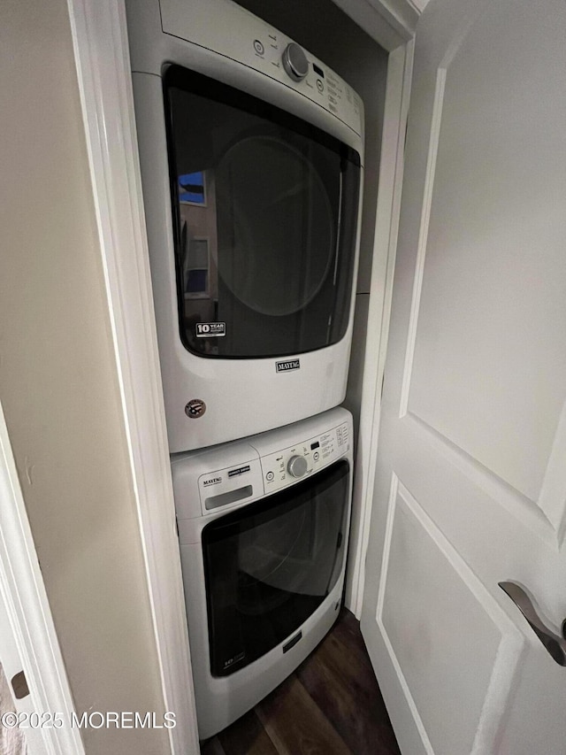 washroom with dark hardwood / wood-style flooring and stacked washer / drying machine