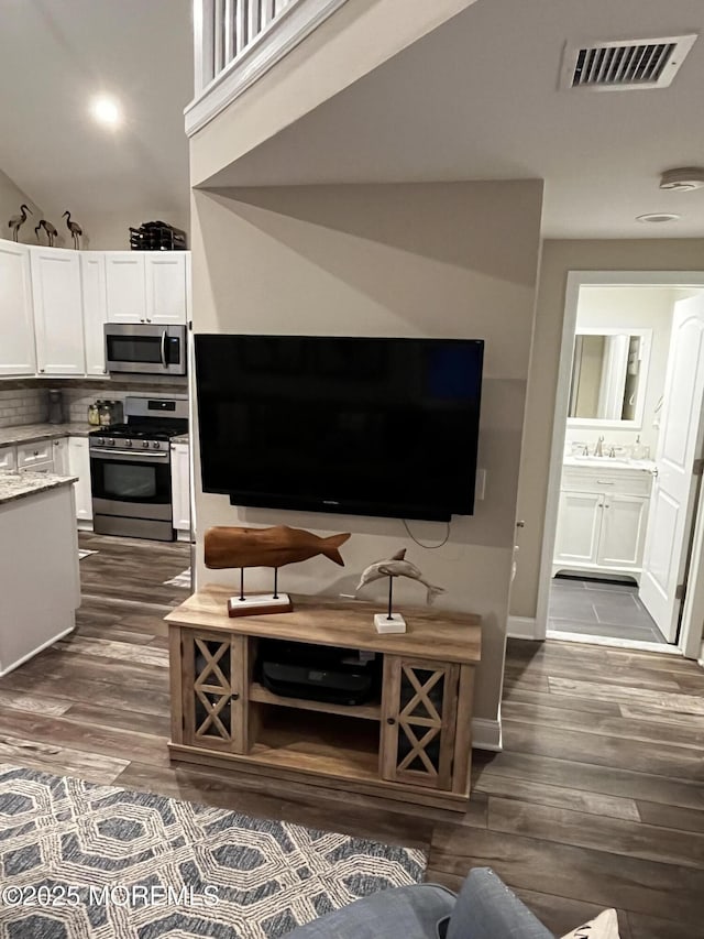 kitchen featuring sink, appliances with stainless steel finishes, dark hardwood / wood-style floors, white cabinets, and backsplash