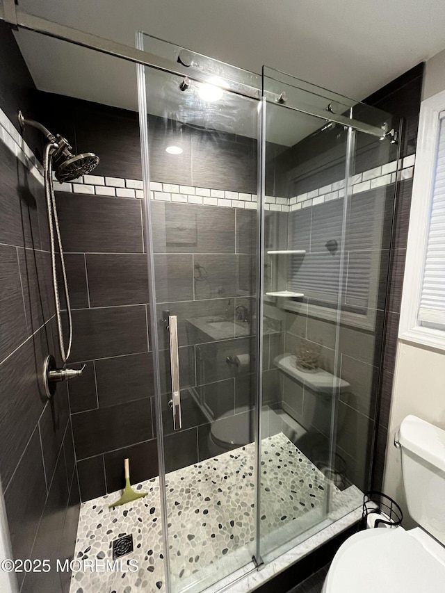 bathroom with a shower with door and toilet