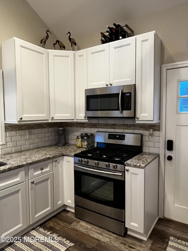 kitchen featuring appliances with stainless steel finishes, dark hardwood / wood-style floors, light stone counters, tasteful backsplash, and white cabinets