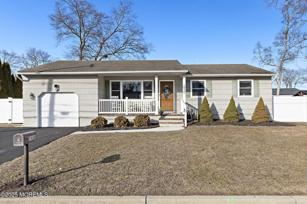 single story home featuring a porch, a garage, and a front yard