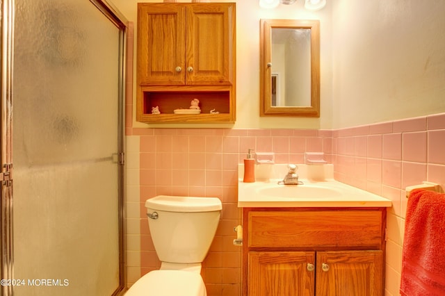 bathroom with vanity, a shower with shower door, tile walls, and toilet