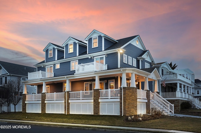 view of front facade featuring a porch, a balcony, and a lawn