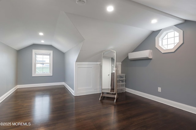 additional living space with an AC wall unit, dark hardwood / wood-style floors, and lofted ceiling