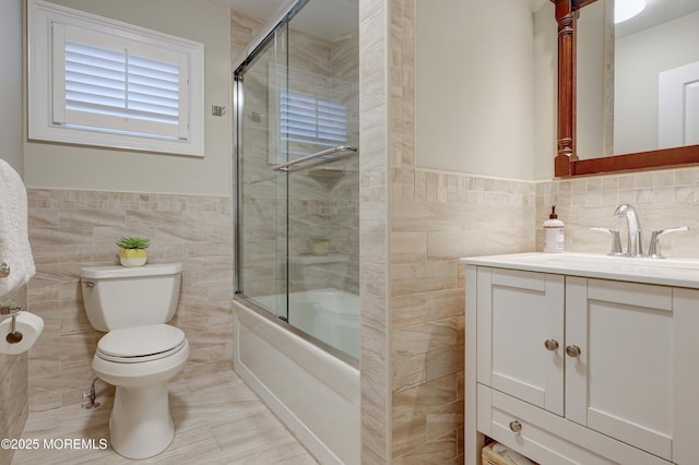 full bathroom with enclosed tub / shower combo, vanity, toilet, and tile walls