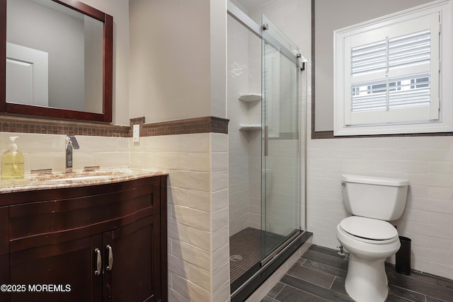 bathroom featuring tile walls, an enclosed shower, vanity, and toilet