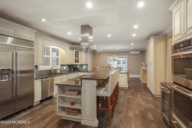 kitchen featuring appliances with stainless steel finishes, island range hood, ornamental molding, a kitchen island, and decorative light fixtures