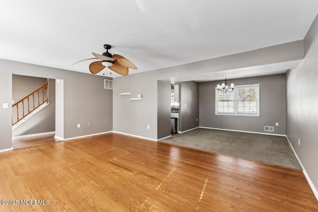 unfurnished living room with hardwood / wood-style flooring and ceiling fan with notable chandelier