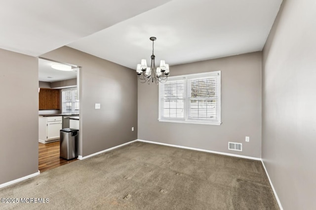 unfurnished room featuring an inviting chandelier, plenty of natural light, and carpet flooring