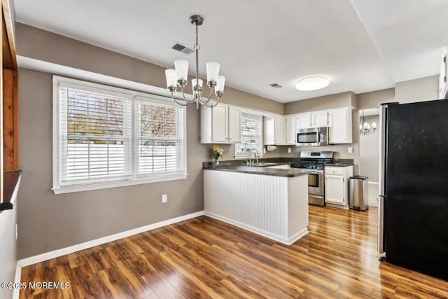 kitchen featuring white cabinetry, appliances with stainless steel finishes, and a notable chandelier