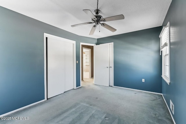 unfurnished bedroom featuring ceiling fan, light carpet, and a textured ceiling